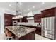 Gourmet kitchen featuring dark wood cabinetry, granite counters, stainless appliances, and a large kitchen island at 2308 E Aster Dr, Chandler, AZ 85286