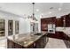 A spacious kitchen with dark wood cabinetry, stainless steel appliances, and a granite island with overhead pendant lighting at 2308 E Aster Dr, Chandler, AZ 85286