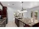 A bright kitchen features dark cabinetry, stainless appliances, a granite island, and views into a dining room and outdoor patio at 2308 E Aster Dr, Chandler, AZ 85286