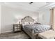 A serene main bedroom displays a tufted headboard, accent lamps, and a bench at the foot of the bed, on wood floors at 2308 E Aster Dr, Chandler, AZ 85286