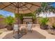 Relaxing outdoor area with an umbrella, fireplace, and comfortable seating perfect for entertaining guests at 2308 E Aster Dr, Chandler, AZ 85286