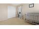 Cozy Bedroom featuring a crib, bookshelf, and neutral-toned walls and carpet at 36265 W Alhambra St, Maricopa, AZ 85138