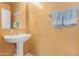 Bright half-bathroom featuring a pedestal sink, mirror, and towel rack with fresh blue towels at 36265 W Alhambra St, Maricopa, AZ 85138