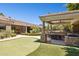Backyard featuring a covered outdoor kitchen, putting green, stone fireplace, and manicured landscaping at 3731 E Halifax Cir, Mesa, AZ 85205