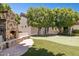 Backyard showcasing stone fireplace, putting green, and mature trees at 3731 E Halifax Cir, Mesa, AZ 85205