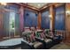 Enjoy movies in this plush home theater, complete with tiered seating, a projector, and custom wall finishes at 3731 E Halifax Cir, Mesa, AZ 85205