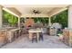 A fully equipped outdoor kitchen includes stainless steel appliances, pizza oven, bar seating and stone accents at 3731 E Halifax Cir, Mesa, AZ 85205