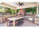 Outdoor kitchen and covered patio with pizza oven, stone counters, and ample seating at 3731 E Halifax Cir, Mesa, AZ 85205