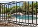 View through wrought iron fence of backyard pool, rock waterfall feature, and mature landscaping at 3731 E Halifax Cir, Mesa, AZ 85205