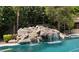 Backyard pool showcasing rock waterfall feature, blue water, and mature landscaping at 3731 E Halifax Cir, Mesa, AZ 85205