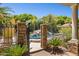 View of backyard pool with stone gate, black wrought iron fence, lush landscaping, and water feature at 3731 E Halifax Cir, Mesa, AZ 85205