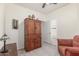 Cozy bedroom featuring a rustic wooden cabinet, comfortable armchair, and soft gray carpeting at 40089 W Bonneau St, Maricopa, AZ 85138