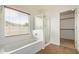 Well-lit bathroom with a bathtub, glass shower, and large window at 41158 W Cahill Dr, Maricopa, AZ 85138