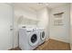 Bright laundry room with washer, dryer, and a storage shelf at 41158 W Cahill Dr, Maricopa, AZ 85138