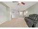Spacious living room features neutral walls, carpet floors, a ceiling fan, and a comfortable leather sofa at 41158 W Cahill Dr, Maricopa, AZ 85138