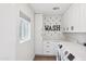 Clean and organized laundry room with white cabinetry, modern appliances, and a 'WASH' themed wall decor at 4320 N 35Th St, Phoenix, AZ 85018