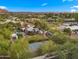 Aerial view of a property featuring a pool, tennis court, lush landscaping, and charming architecture, surrounded by greenery at 4824 E Hummingbird Ln, Paradise Valley, AZ 85253