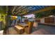 Cozy outdoor kitchen and dining area under a pergola with string lights, creating a perfect ambiance for evening gatherings at 4824 E Hummingbird Ln, Paradise Valley, AZ 85253