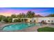Inviting pool with a rock waterfall feature and outdoor fireplace, set against a backdrop of desert landscaping and a colorful sky at 4824 E Hummingbird Ln, Paradise Valley, AZ 85253