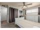 Bedroom features neutral carpet, ceiling fan, white dressers and large window at 520 N Stapley Dr # 117, Mesa, AZ 85203