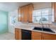 Functional kitchen features warm wood cabinets, a black dishwasher, and a convenient double basin sink under a window at 6121 N 11Th St, Phoenix, AZ 85014