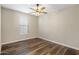 A cozy bedroom featuring wood-look flooring, neutral walls, a ceiling fan, and a window for natural light at 6623 E Marisa Ln, Phoenix, AZ 85054