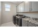 A modern laundry room featuring granite countertops, gray cabinetry, and stainless steel washer and dryer at 6623 E Marisa Ln, Phoenix, AZ 85054