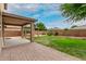 Expansive backyard featuring a covered patio, green lawn, mature trees, and privacy fencing for outdoor enjoyment at 7812 S 67Th Ln, Laveen, AZ 85339