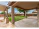 Spacious backyard showcasing a covered patio with stone pillars, a lush green lawn, and mature landscaping at 7812 S 67Th Ln, Laveen, AZ 85339