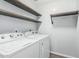 Functional laundry room with front loading washer, dryer, and shelving for organizing supplies at 10440 E Osage Ave, Mesa, AZ 85212
