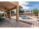 Relaxing covered patio with fan overlooking the sparkling pool and lush green lawn at 10440 E Osage Ave, Mesa, AZ 85212