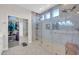 Bright glass shower featuring tiled walls, built-in shelving, and shower bench with walk-in closet at 10613 E Knowles Ave, Mesa, AZ 85209