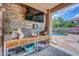 Covered outdoor patio with stone accent wall, television, and view of backyard pool at 10613 E Knowles Ave, Mesa, AZ 85209
