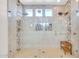 Bright glass shower featuring tiled walls, built-in shelving, shower bench, and dual shower heads at 10613 E Knowles Ave, Mesa, AZ 85209