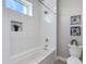 Bathroom featuring a tiled bathtub with glass shower, toilet and built-in shelving, and large window at 1111 E Missouri Ave # 9, Phoenix, AZ 85014