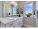 Bright bathroom featuring a large mirror, window, and a modern single sink vanity with storage at 1111 E Missouri Ave # 9, Phoenix, AZ 85014