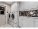 Well-lit laundry room with ample storage, mosaic backsplash, washer, dryer and a sink at 14001 N 34Th Dr, Phoenix, AZ 85053