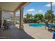Covered back patio with outdoor seating and a grill overlooking a pool and lush landscaping at 15753 W Kino Dr, Surprise, AZ 85374