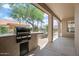 Covered back patio with built-in grill, overlooking the backyard with desert plants and mature trees at 15989 W Indianola Ave, Goodyear, AZ 85395