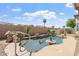 Backyard pool surrounded by desert landscaping with seating, tropical plants, and rock features at 15989 W Indianola Ave, Goodyear, AZ 85395