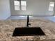 Granite countertop island with a black sink and faucet, and an open view of the living room and natural light at 16006 W Electra Ln, Surprise, AZ 85387
