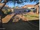 View of the backyard with a charming hanging swing, lush landscaping, and a cozy fire pit area at 17328 W Pinnacle Vista Dr Dr, Surprise, AZ 85387