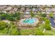 Aerial view of a resort-style community pool surrounded by palm trees, sunbathers, and manicured lawns at 17815 W Straight Arrow Ln, Surprise, AZ 85387
