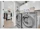 Modern laundry room with silver washer and dryer, white cabinetry, and an adjacent walk-in closet at 17815 W Straight Arrow Ln, Surprise, AZ 85387