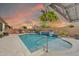Backyard pool area with water features and landscaping, set against a vibrant sky at sunset at 17815 W Straight Arrow Ln, Surprise, AZ 85387