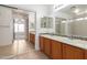 En-suite bathroom with dual sinks, wood cabinetry, and sliding mirrored closet doors at 22672 W Solano Dr, Buckeye, AZ 85326
