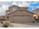 Exterior view of a home showcasing a large two-car garage and desert-style landscaping at 22672 W Solano Dr, Buckeye, AZ 85326
