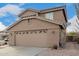 A tan two-story house with a two-car garage and desert landscaping along the driveway at 22672 W Solano Dr, Buckeye, AZ 85326