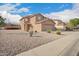 Tan two-story home with desert landscaping and a view of the sidewalk at 22672 W Solano Dr, Buckeye, AZ 85326