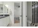 Modern bathroom with stylish black-and-white tiled floor, plus a shower and an open doorway to the bedroom at 24372 N 96Th Ln, Peoria, AZ 85383